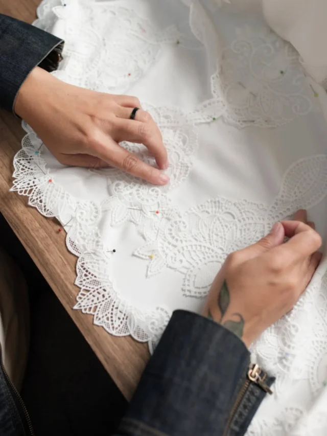 Aplicação de renda à mão durante a confecção de um vestido Louise